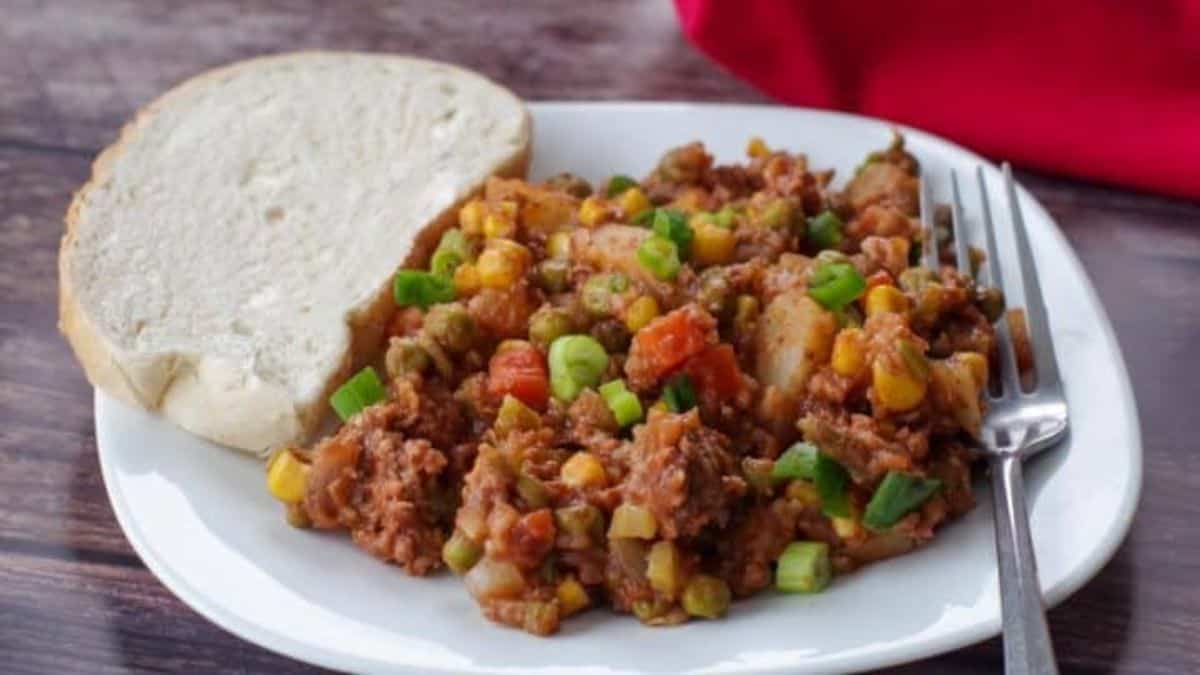 A serving of shipwreck casserole on a plate with bread on the side. 