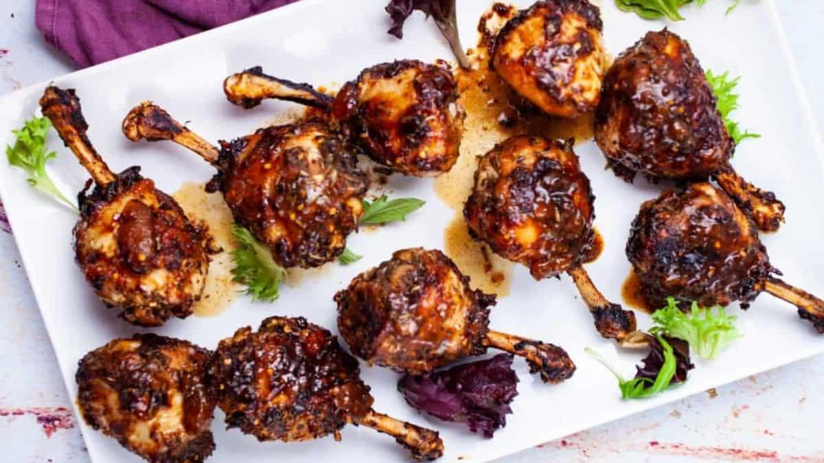 A few pieces of chicken drumstick lollipops are served on a plate.