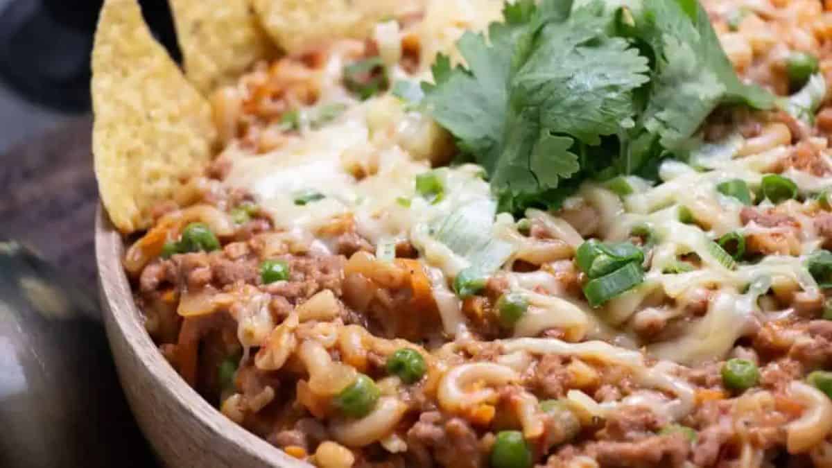 A bowl of chili mac and cheese without beans with tortilla chips on the side.