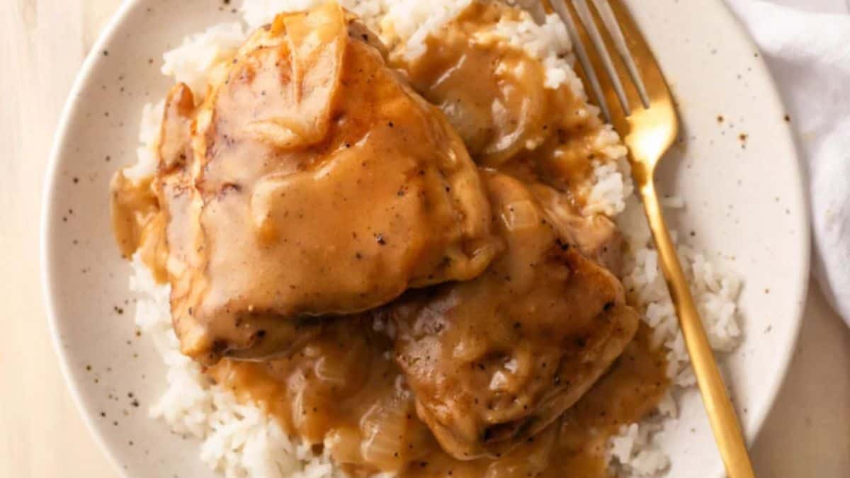 A serving of rice topped with southern chicken thighs and gravy. 