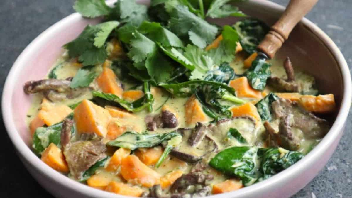 A bowl of vegan & soy free Thai green curry with sweet potato, spinach and mushrooms