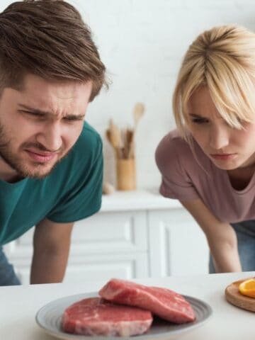 couple staring at meat looking confused