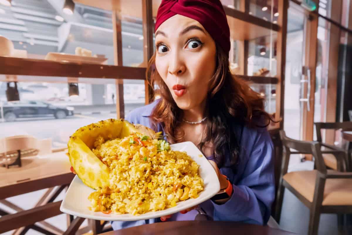 happy woman serving Thai pineapple fried rice
