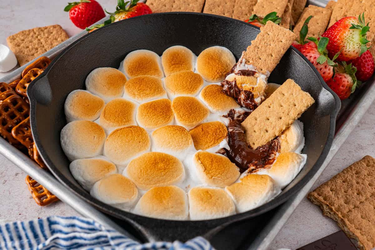 Easy S'mores Dip in Cast Iron Skillet with graham crackers dip on it.