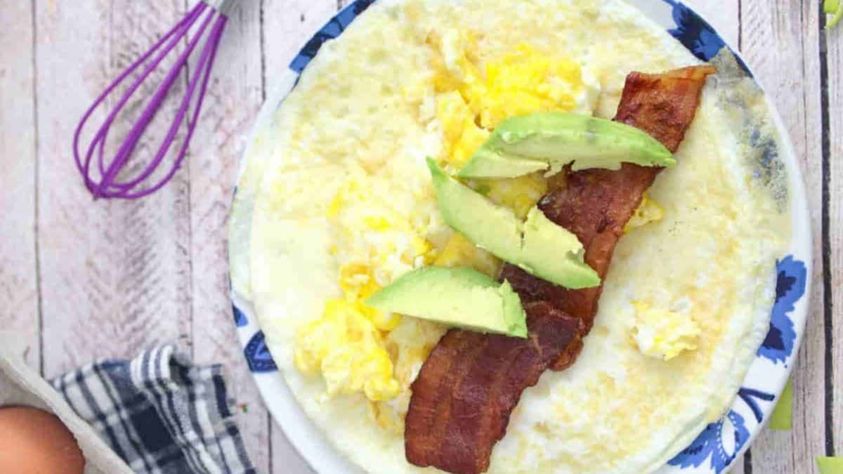 2-Ingredient Egg White Wraps served on a plate with bacon, egg, and some guacamole. 