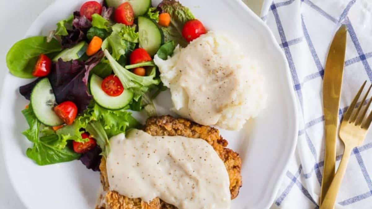 Chicken Fried Steak served with mashed potatoes and a side salad on a plate.