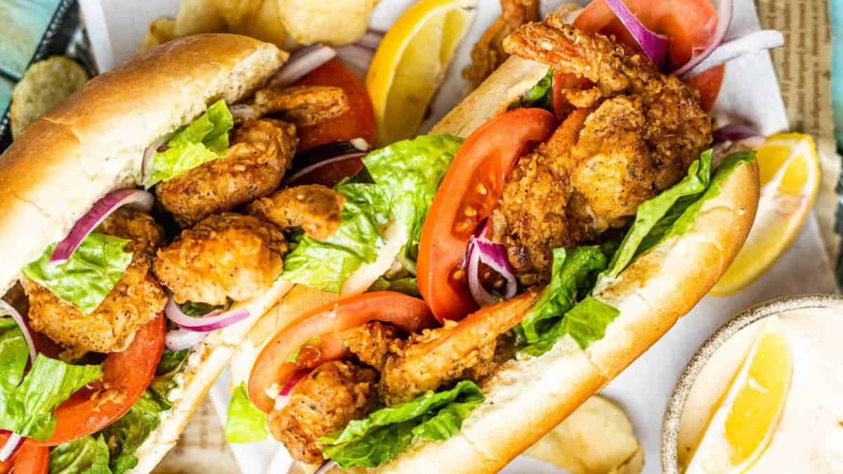 Crispy Shrimp Po’Boy with Old Bay Sauce served in a bun with lettuce and tomato slices.
