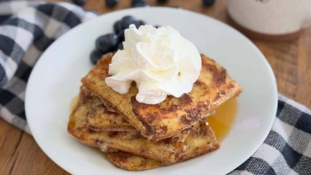 A serving of Keto French Toast topped with whipped cream, syrup and berries.