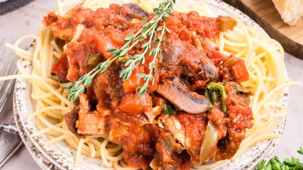 Easy One Pot Chicken Cacciatore With Shredded Chicken, served over spaghetti noodles on a plate.
