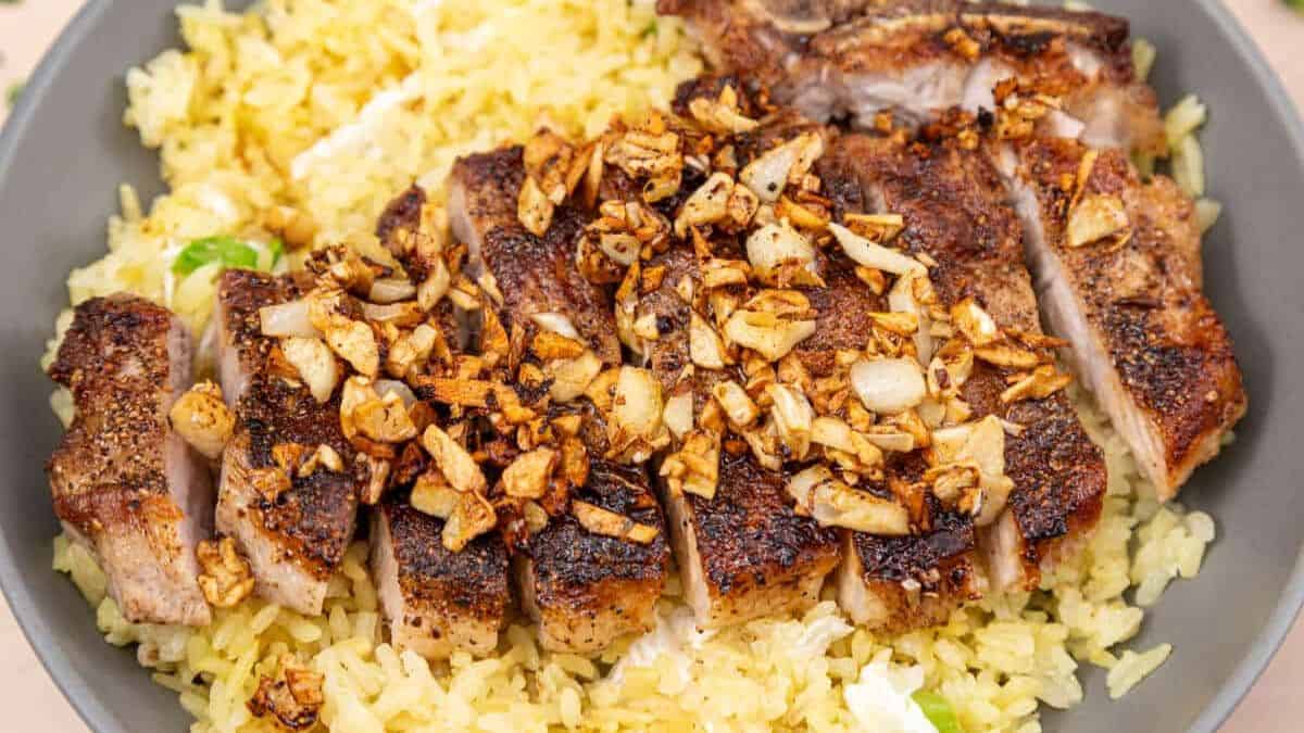 Garlic Pork Chops on top of fried rice served in a bowl. 