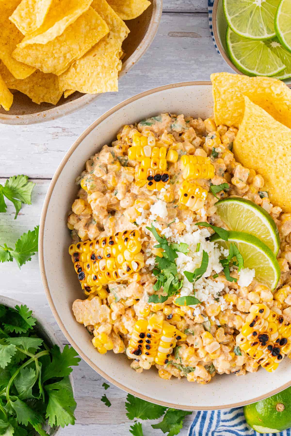 A bowl of Mexican Street Corn Dip with lime wedges on top