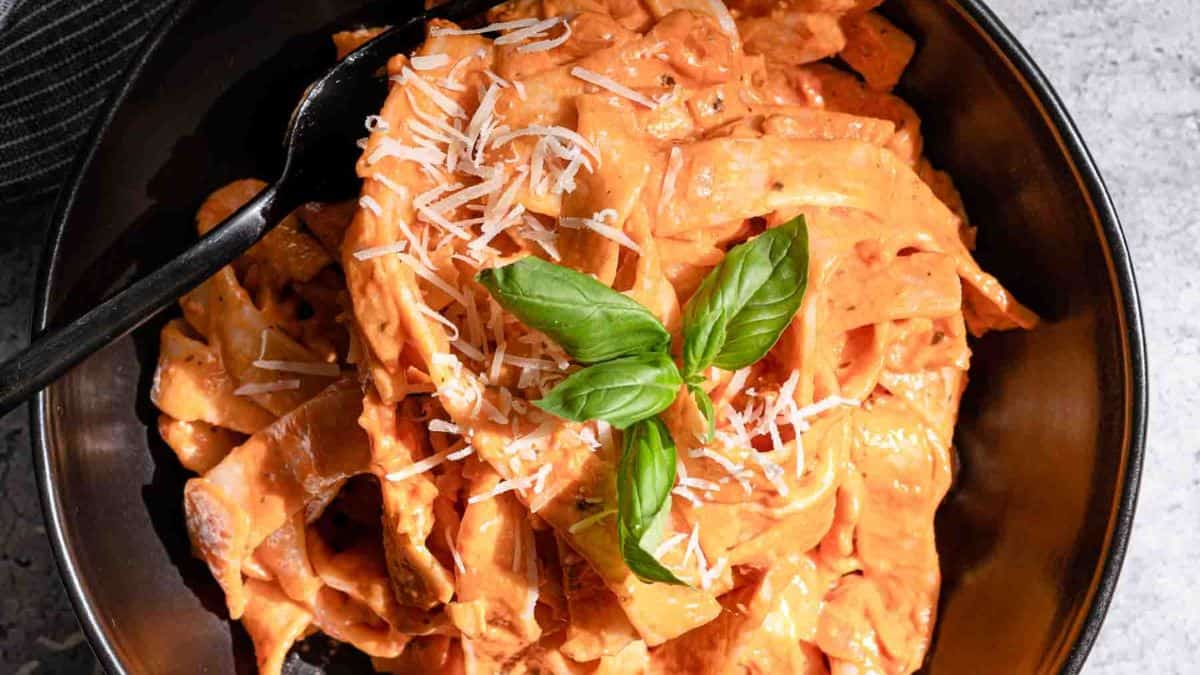 A single serving of Pink Pasta topped with fresh leaves of basil.