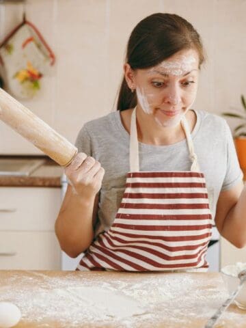 confused woman covered in flour in kitchen