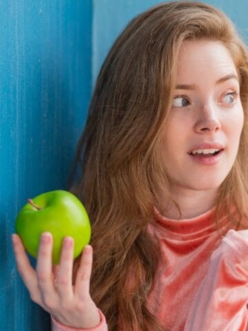 confused woman holding apple