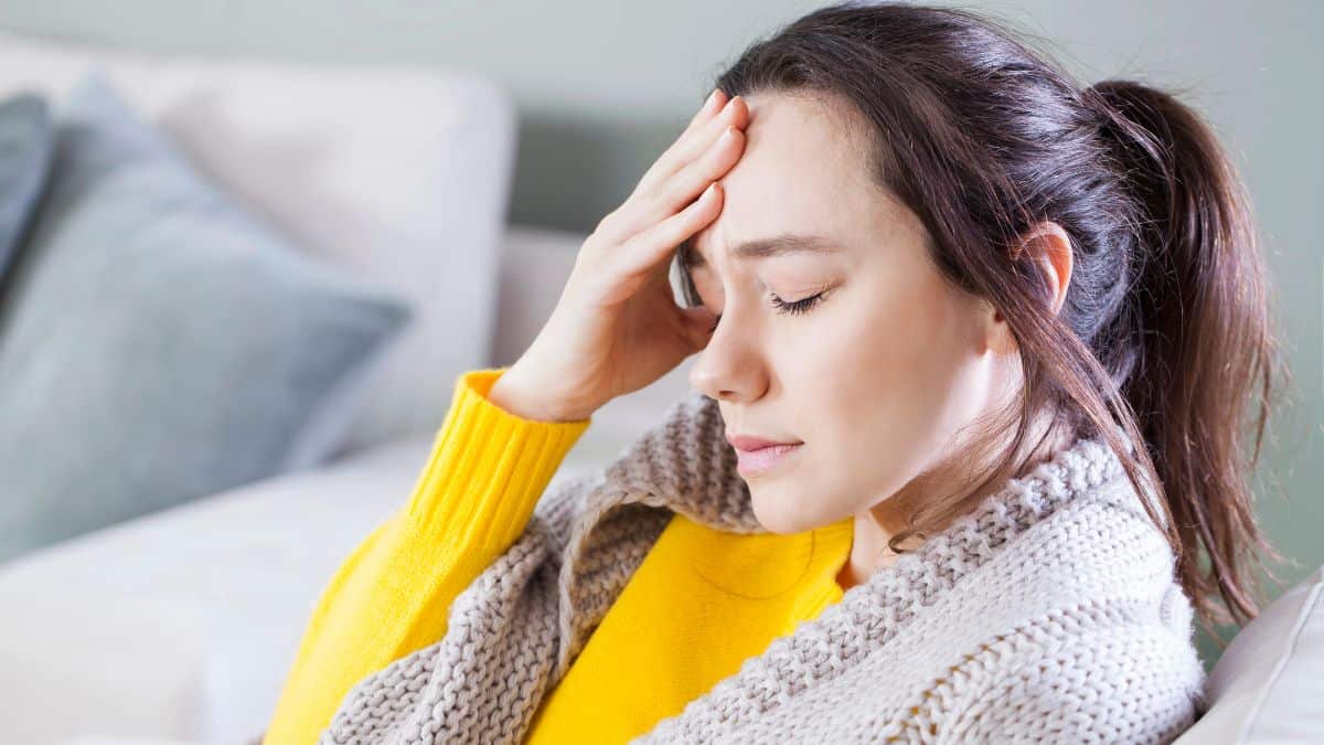 sick woman with headache on couch
