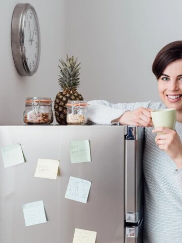 woman leaning on fridge with coffee