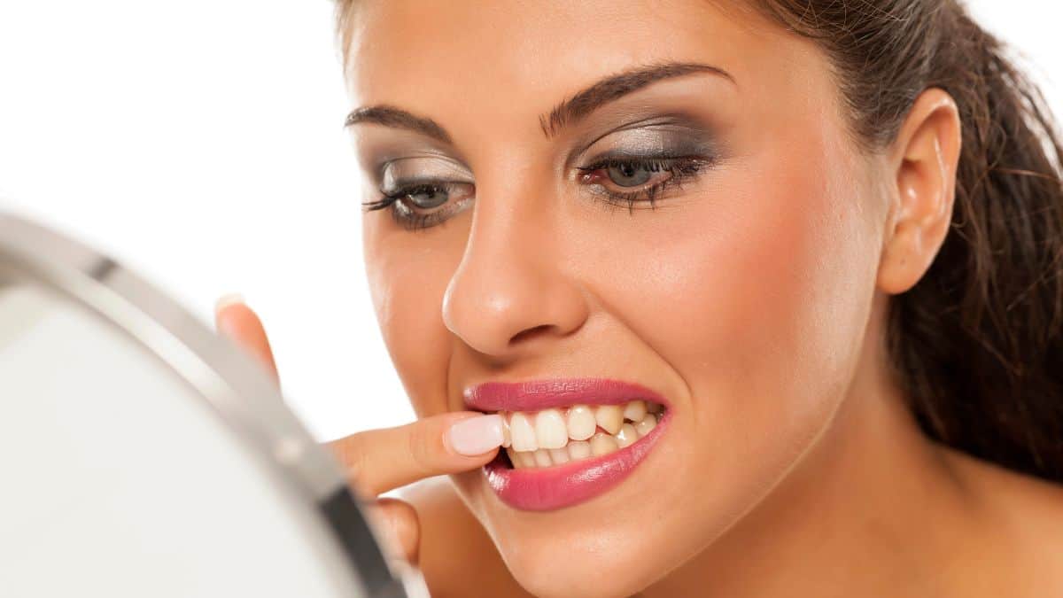 woman looking at teeth in mirror