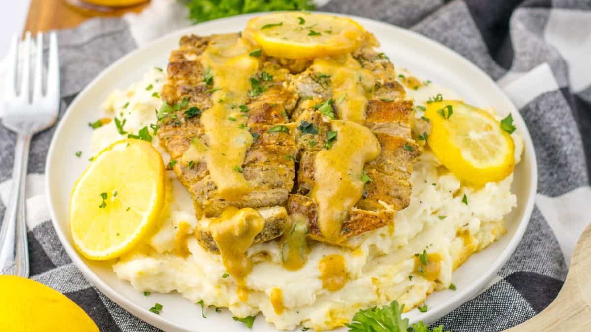 A serving of Lemon Butter Chicken on a bed of mashed potatoes.