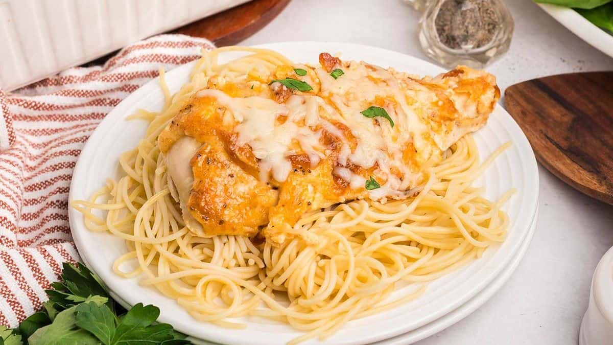 A serving of Melt in Your Mouth Chicken on a plate of spaghetti pasta.