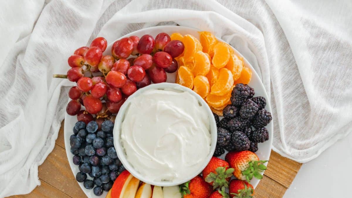 Quick and Delicious Fruit Dip served in a bowl with a platter of fruits.