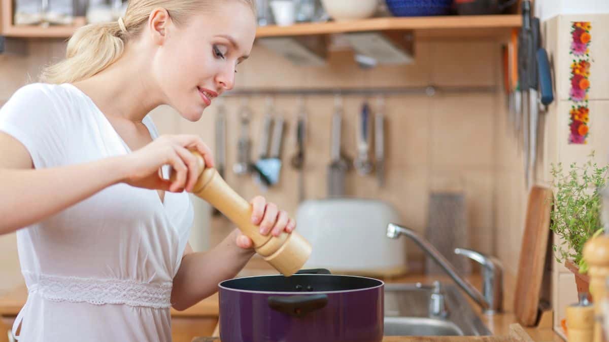 woman cooking with pot and pepper mill