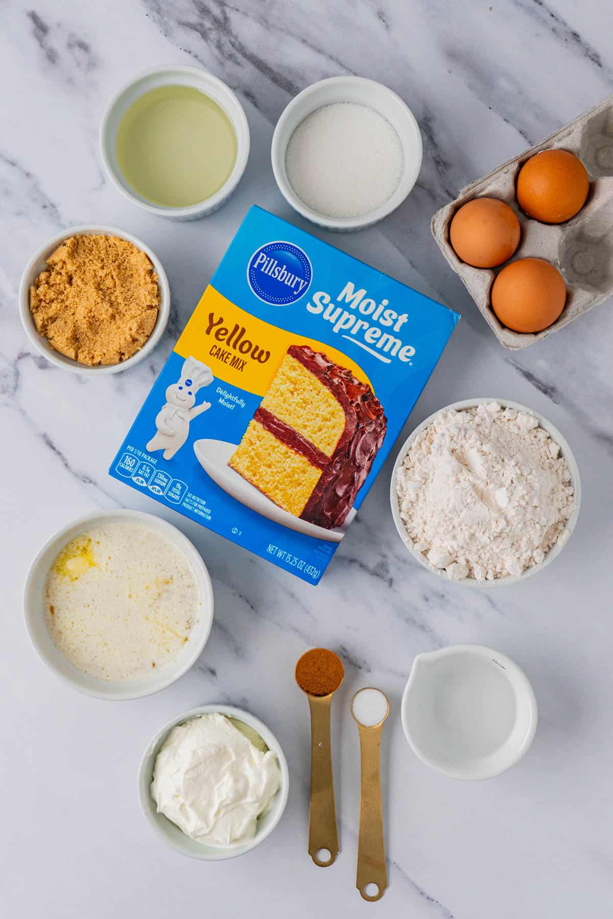 Flat lay of ingredients for the Cake Mix Coffee Cake With Yellow Cake: eggs, flour, a box of yellow cake mix, butter, sugar, spices, oil, salt, water.