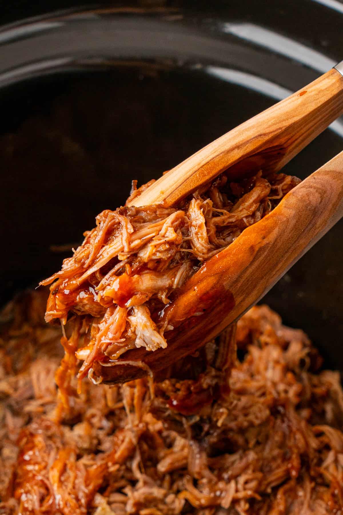 Crockpot BBQ Pulled Pork with a wooden thong getting a portion from a crockpot.