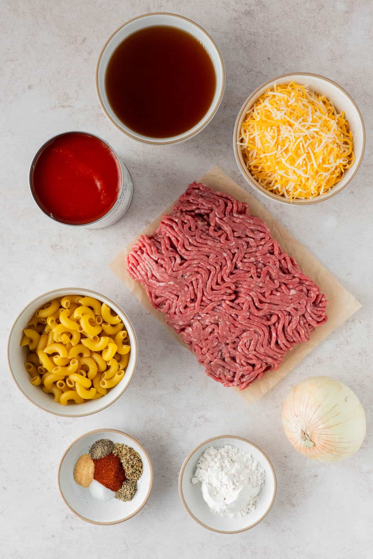 Ingredients for Homemade Cheesy Hamburger Helper: ground meat, macaroni, shredded cheese, canned tomato, beef broth, spices, flour, onion,