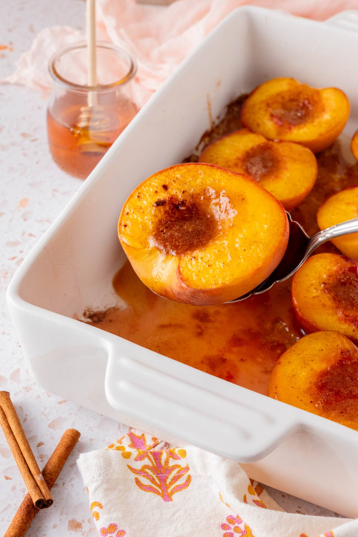 spooning a piece of Honey Roasted Peaches (Oven Baked Peaches)