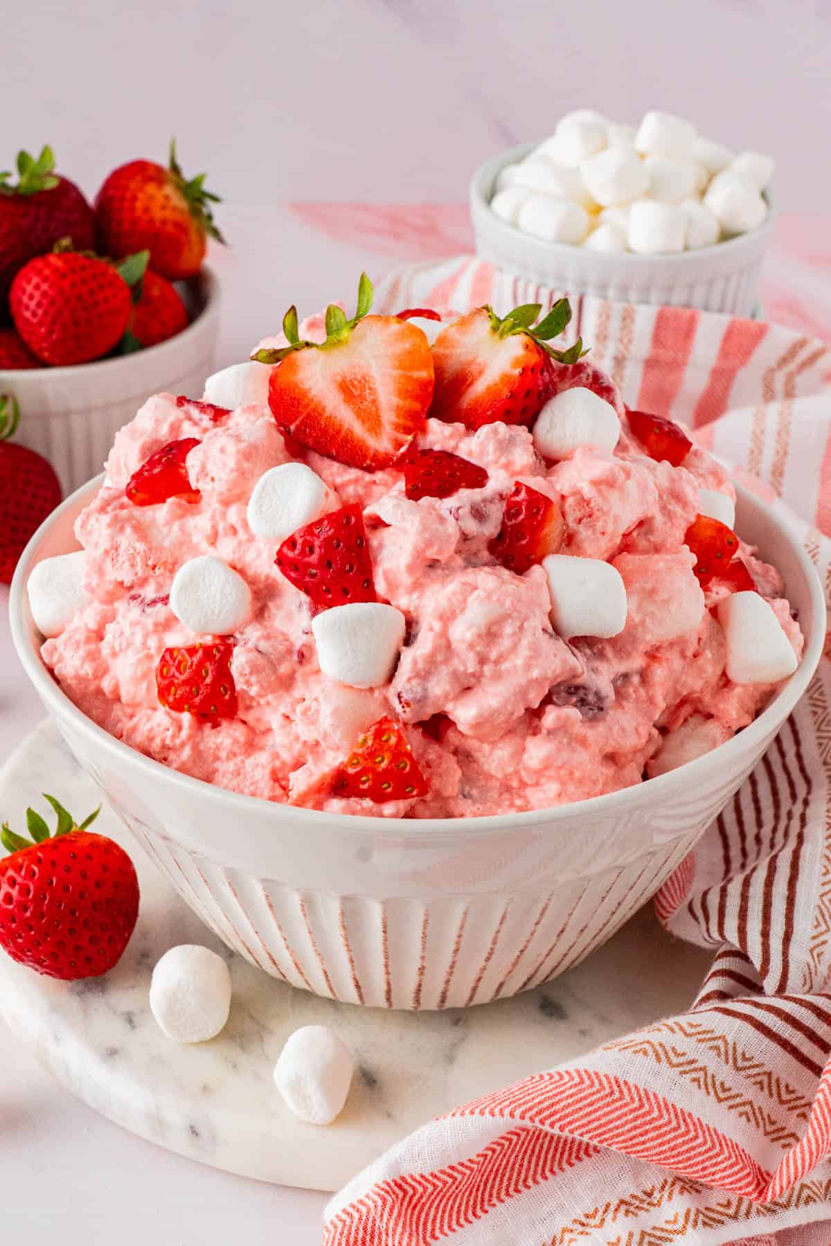 a bowl of Strawberry Fluff Salad with small bowls of white marshmallows and fresh strawberries