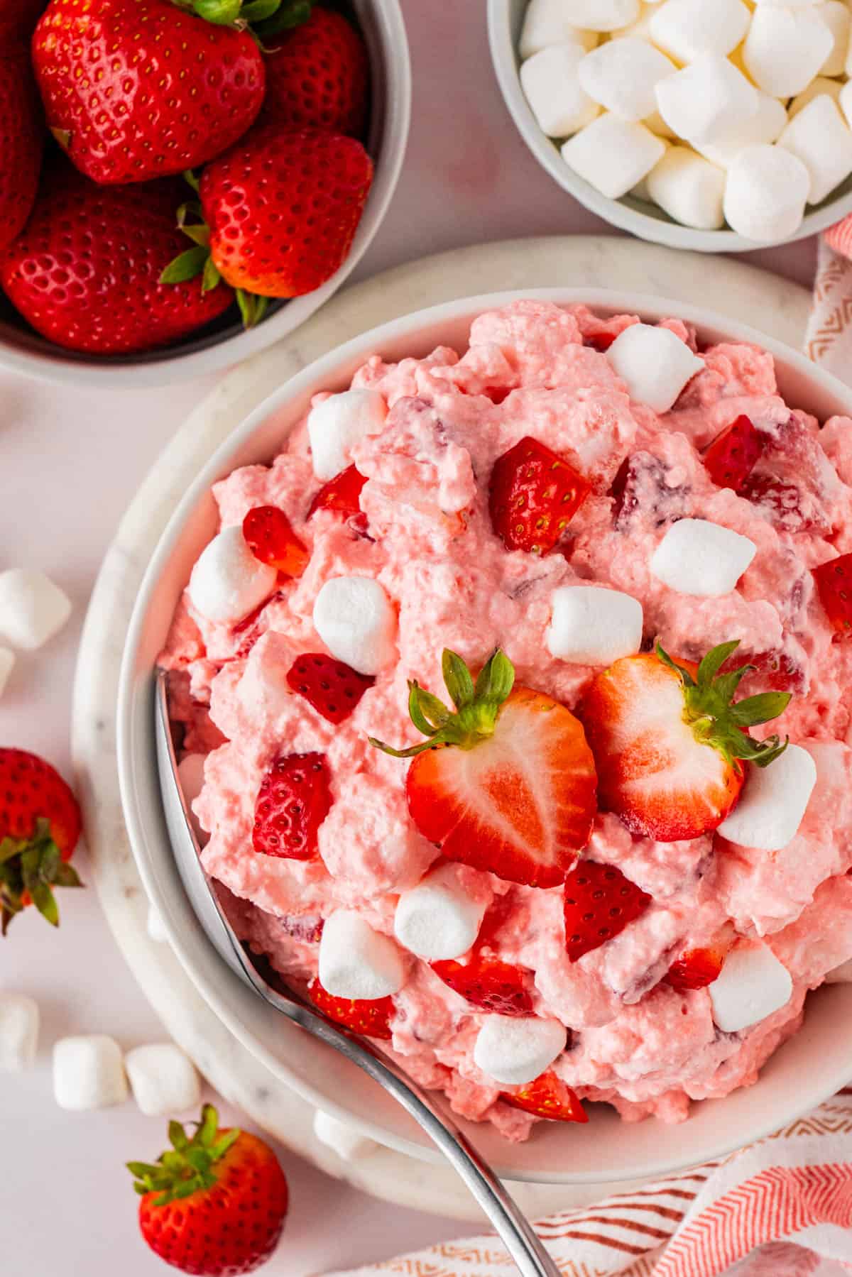 Overhead shot of a bowl of Strawberry Fluff Salad topped with marshmallows and fresh strawberries