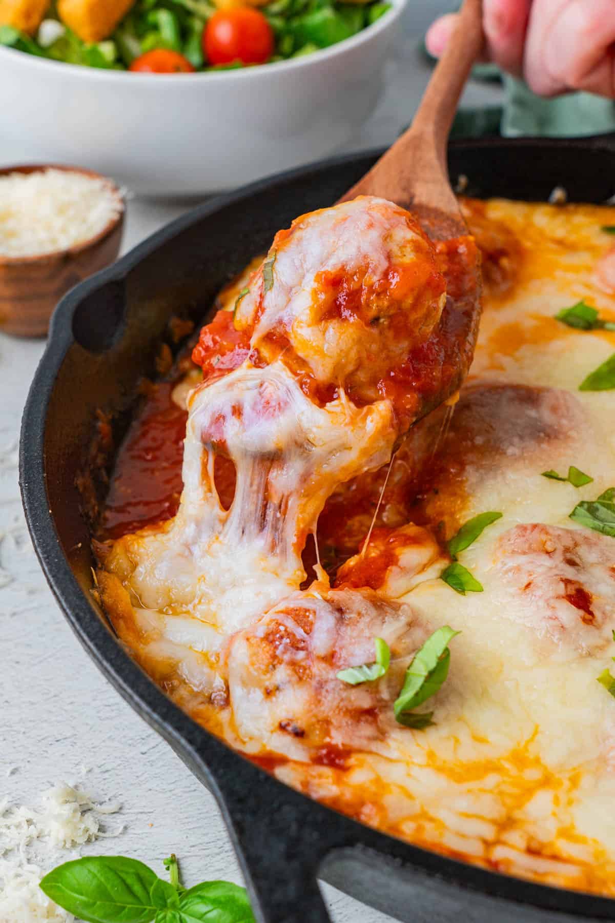 Cheesy Chicken and Rice Casserole Meatballs single piece being pulled out from the serving in a cast iron.