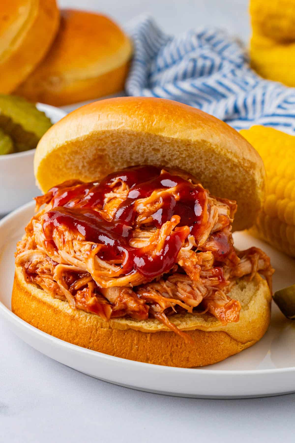 BBQ Chicken Pulled Pork sandwich on a plate with corn cob.