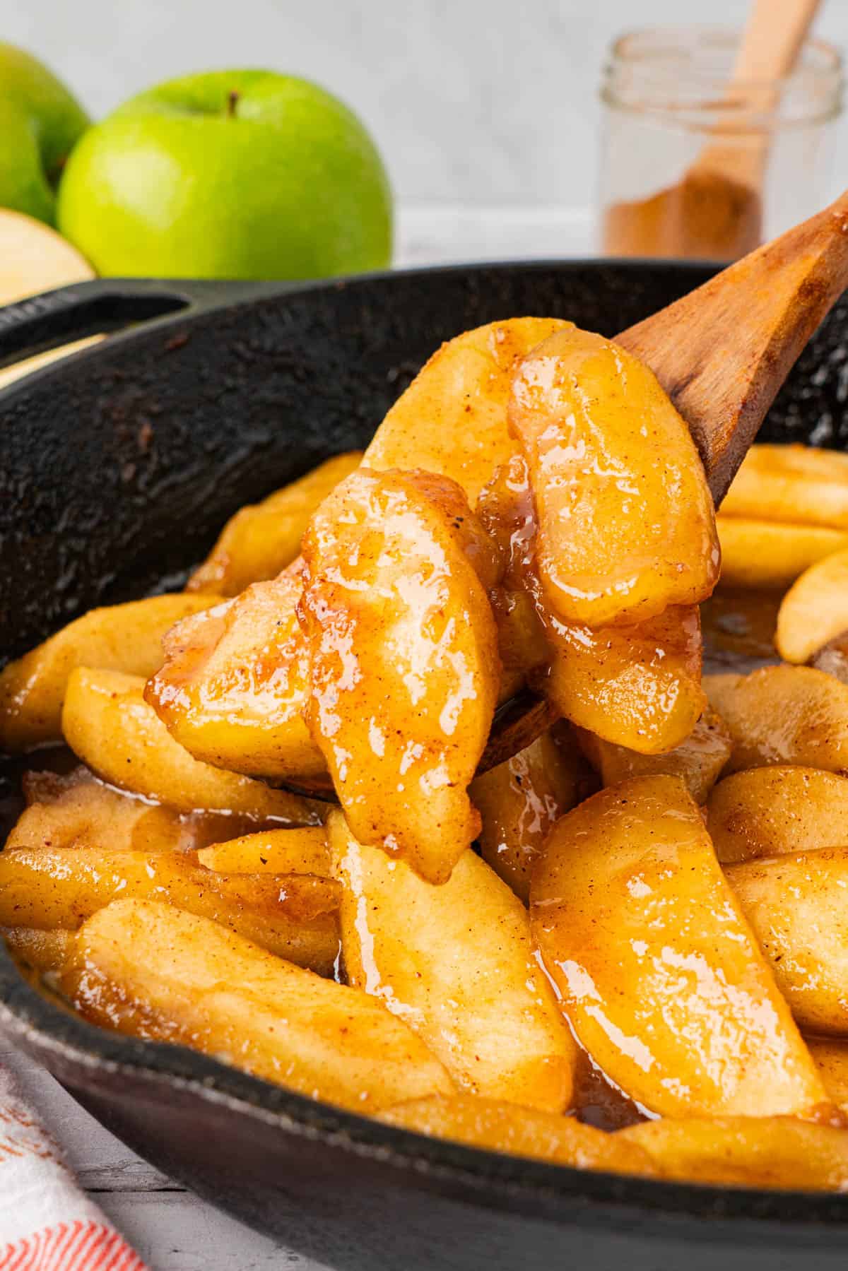 A wooden spoonful of Southern Fried Apples frm a skillet