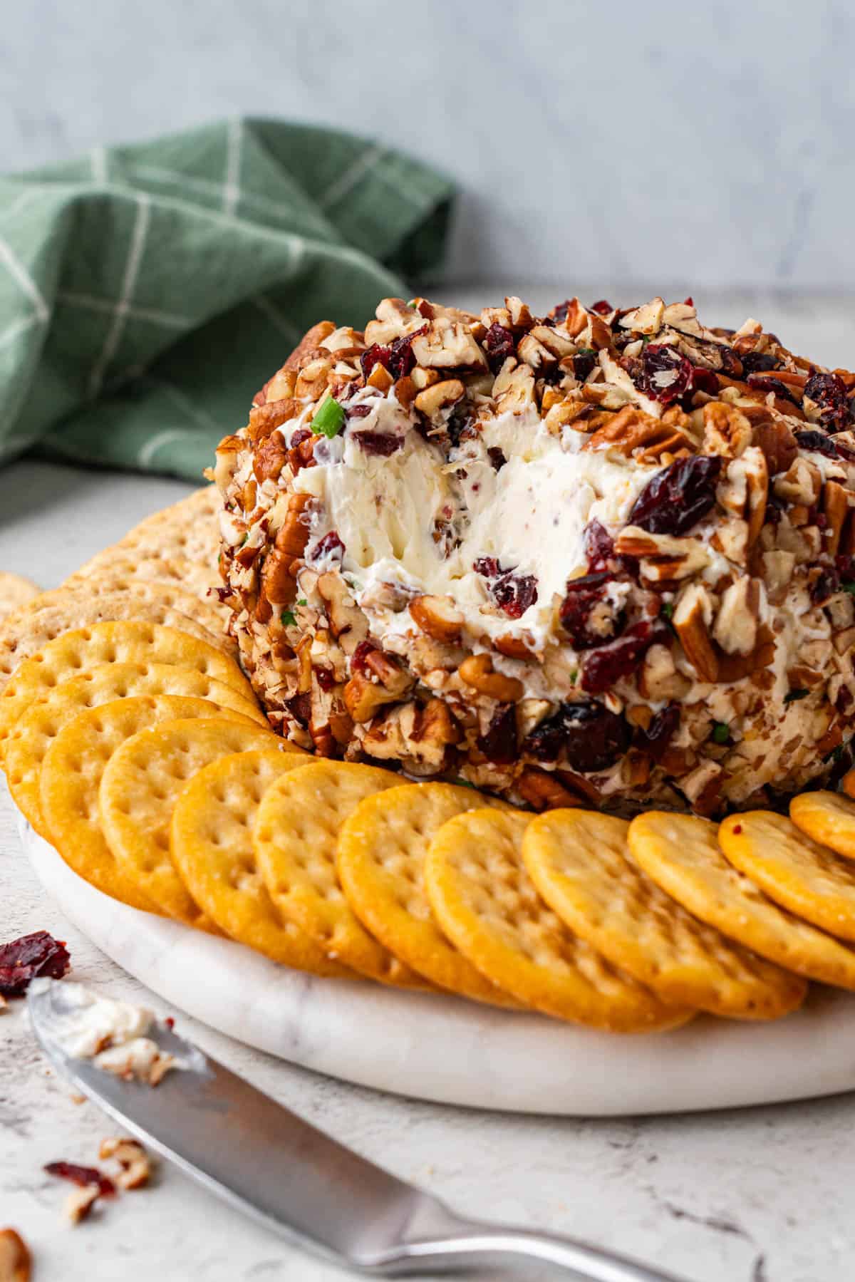 cut Cranberry Pecan Cheese Ball with crackers around the cheeseball