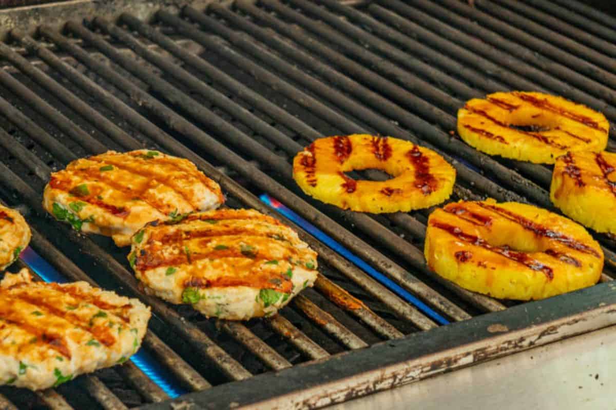 Chicken Patties and sliced pineapples grilled on a griller. 