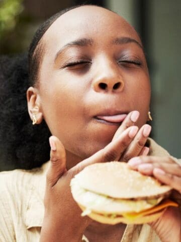 woman licking lips eating sandwich