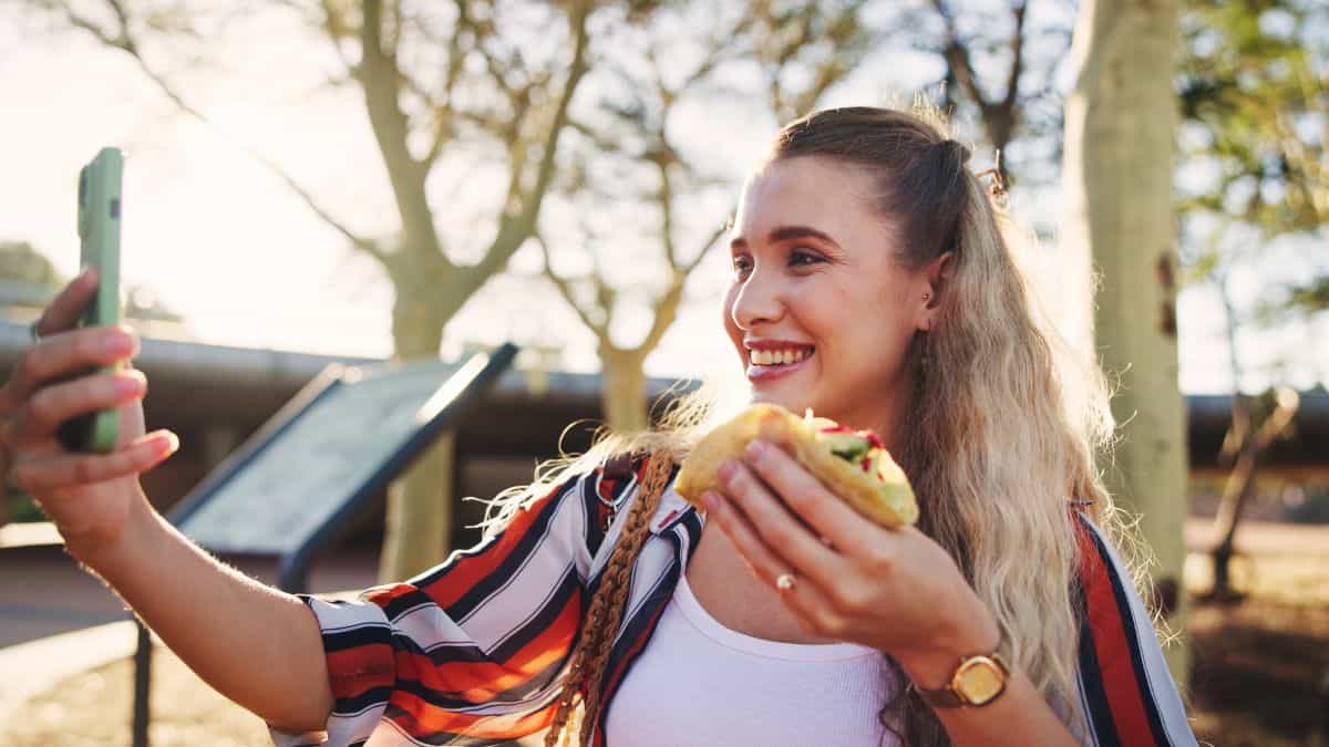 woman taking a selfie with a taco on phone