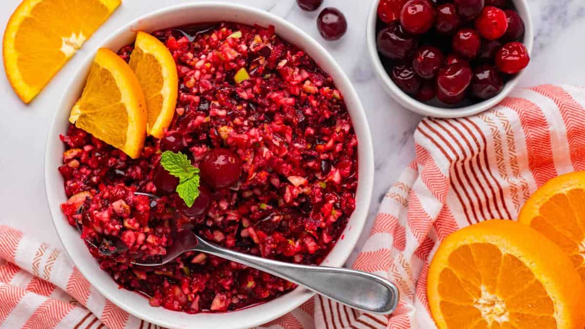 A bowl of Cranberry Orange Relish with some orange slices. 