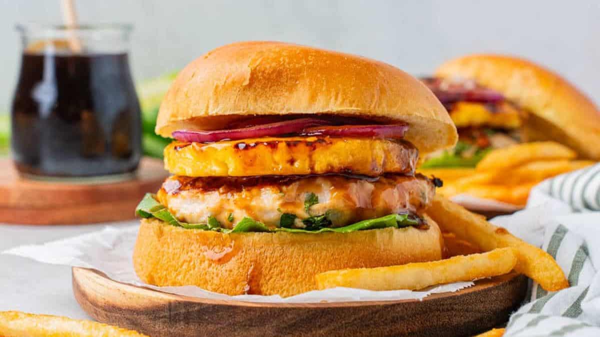 A serving of Teriyaki Chicken Burgers With Grilled Pineapple with side fries.