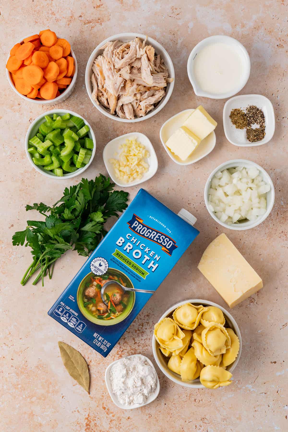 Chicken Tortellini Soup ingredients: Sliced Carrots, Sliced Celery, Shredded Chicken meat, Butter, Spices, Cheese, Heavy Cream, Chicken Broth, Parsley, Cheese Block, Tortellini, Chopped Onion, bay Leaf, Flour.