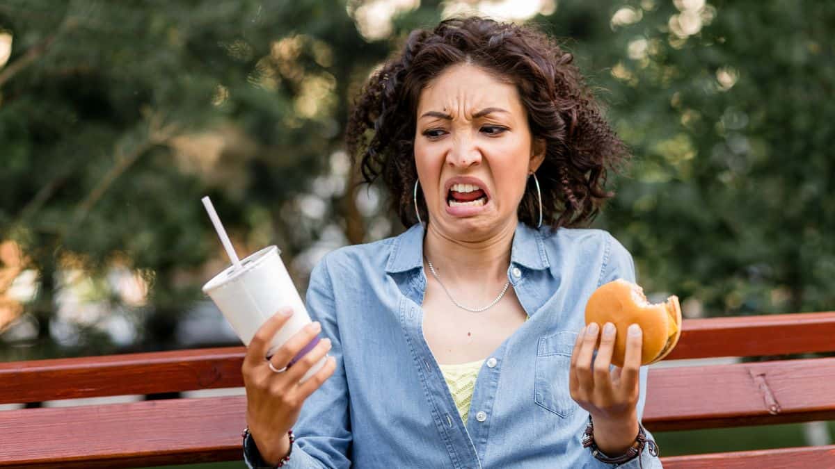 disgusted woman with burger and soda