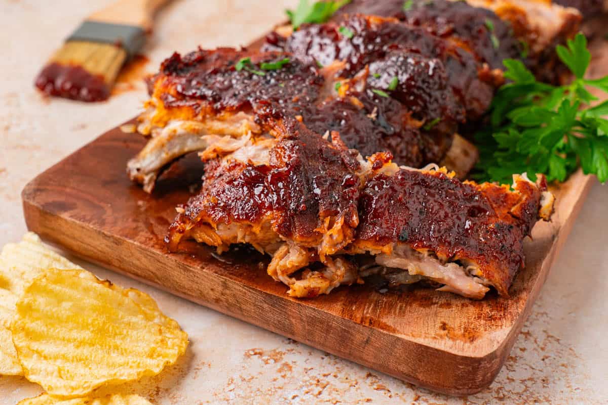 A close-up shot of Baby Back Ribs cut into serving pieces on a wooden serving board. 