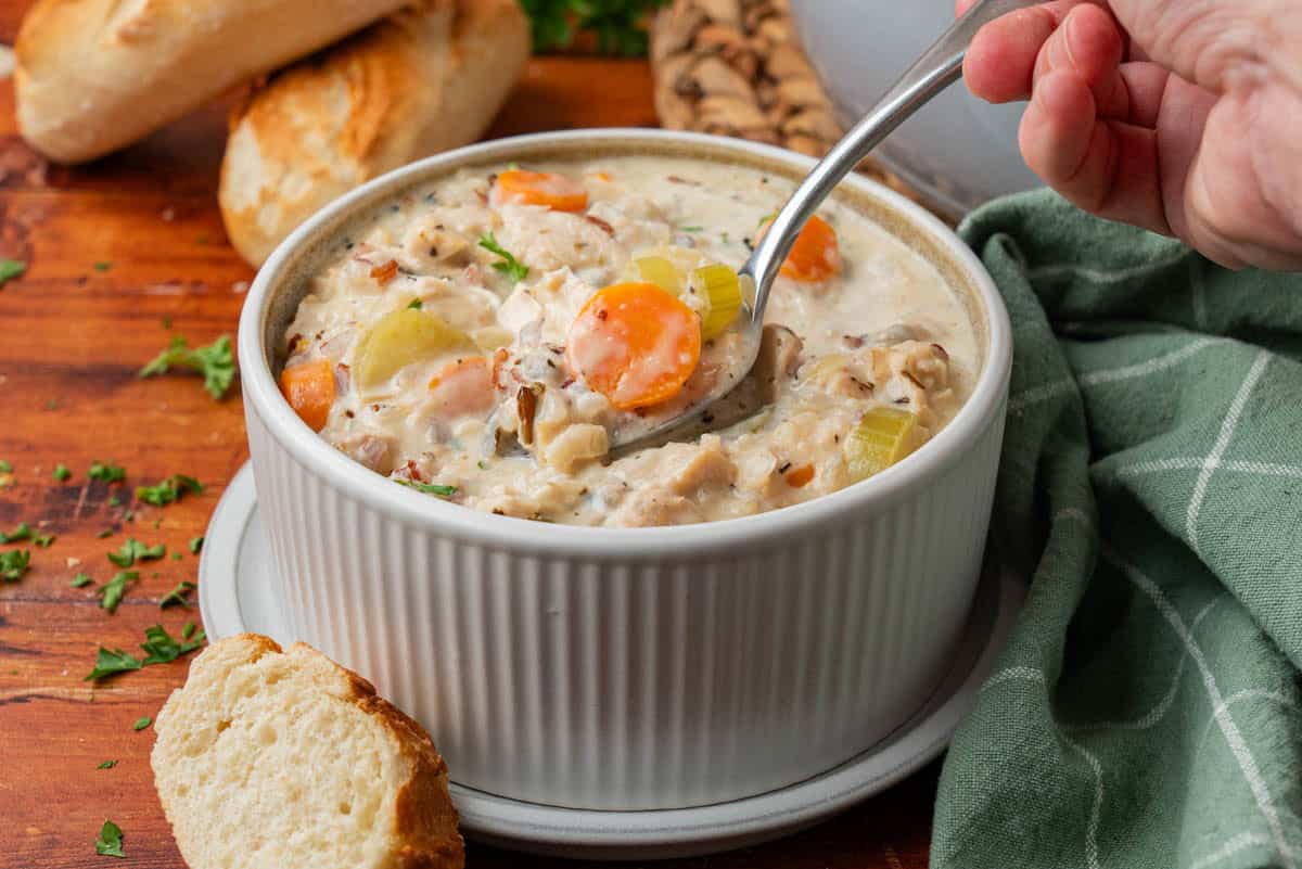 side shot of the bowl of soup, with a hand and spoon diving in!