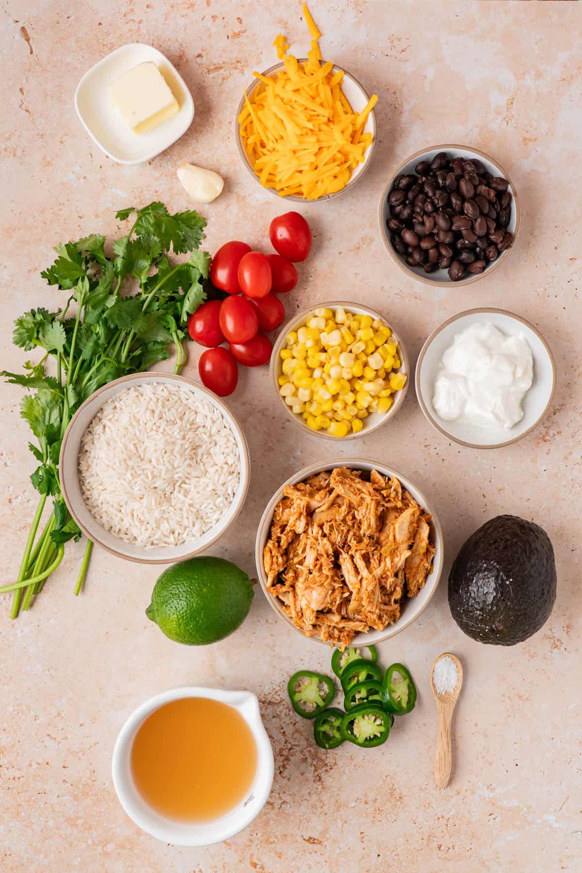 ingredients for burrito bowls are rice, chicken. black beans, corn, sour cream, cilantro, tomatoes, butter, garlic, cheese, lime, avocado, jalapeno, chicken broth and salt.