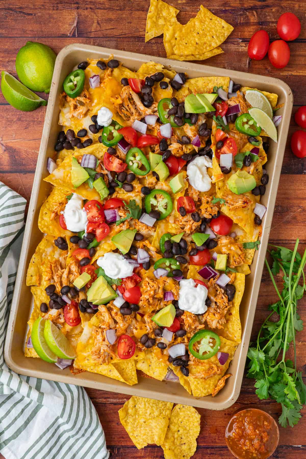A sheet pan with chicken nachos and toppings