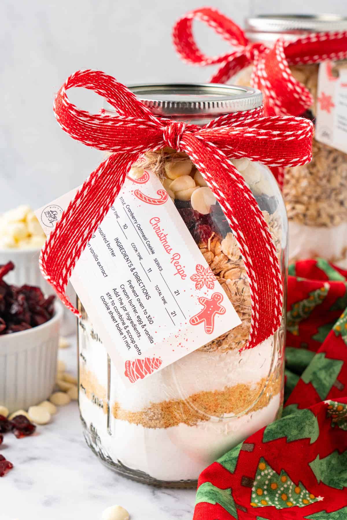 a mason jar cookie recipe layered in a jar with a red ribbon tied in a bow and the recipe instructions printed on a card tied to the jar