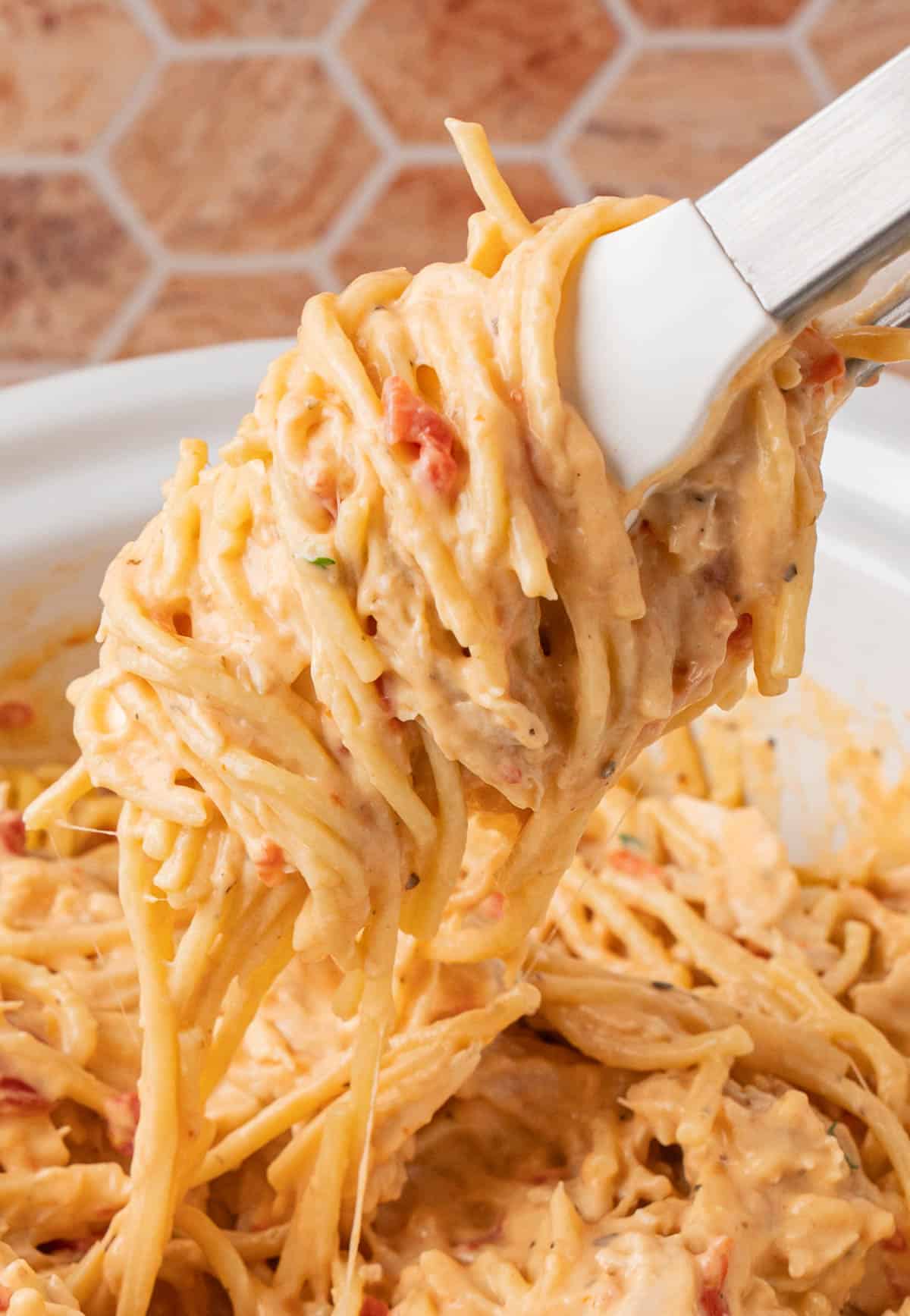 Kitchen tongs with the pasta showing how creamy the dish is