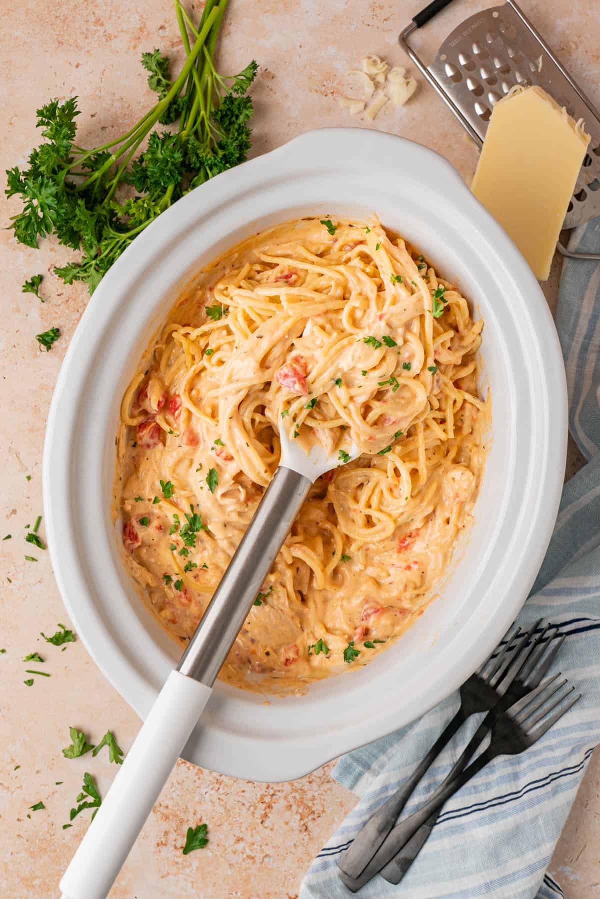 white crockpot with chicken spaghetti and a ladle for serving