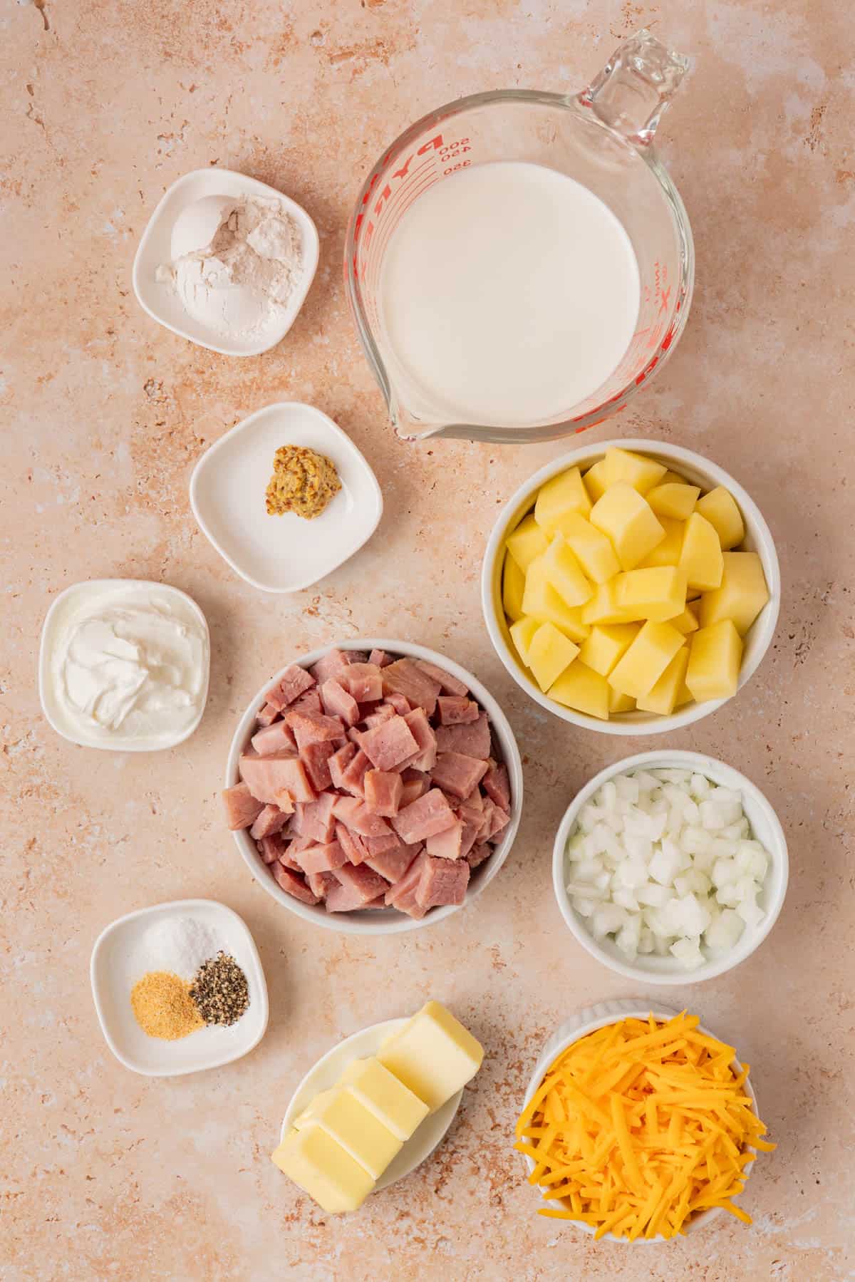 the ingredients for the casserole are potatoes, ham, butter, sour cream, onions, mustard, flour, spices, cheese and half and half